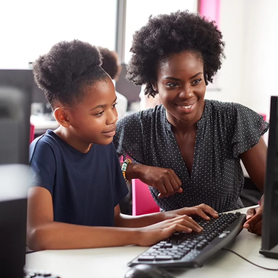 woman helping a child at a computer